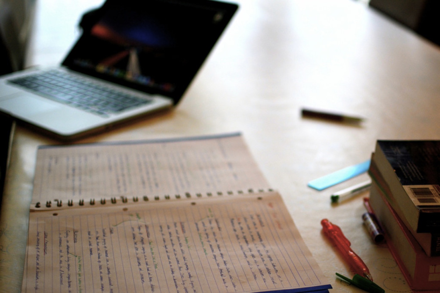 A handwritten notebook open beside a laptop