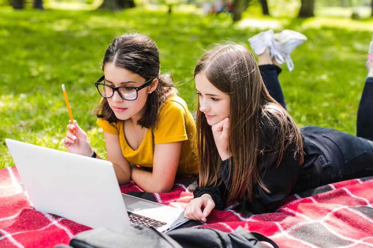 Two students sharing one laptop outdoors