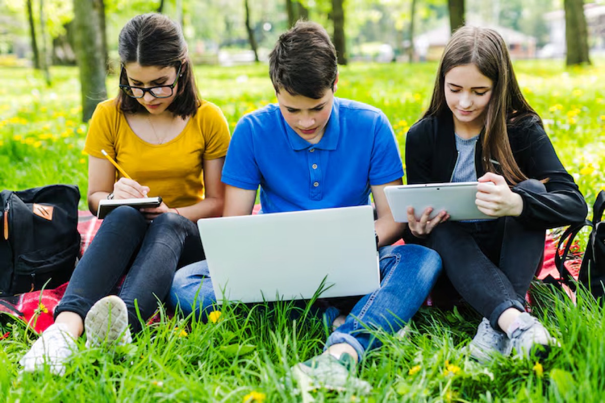 Three students working together on the grass